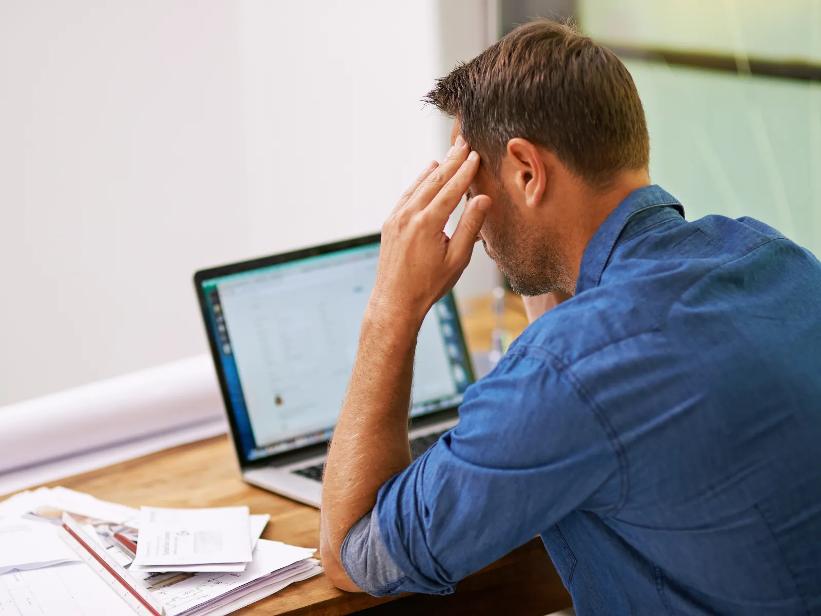 a man sitting at a desk with his hand on his face